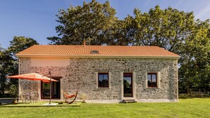 A stone house with a tiled roof, a patio with outdoor furniture, and a hammock. - Peaceful cottage near Nantes - 4 guests (Ligné)