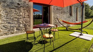 A stone building with a patio, a red umbrella, and a hammock. - Peaceful cottage near Nantes - 4 guests (Ligné)