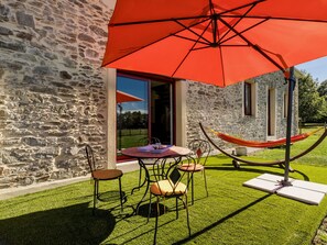 A stone building with a patio, a red umbrella, and a hammock. - Peaceful cottage near Nantes - 4 guests (Ligné)