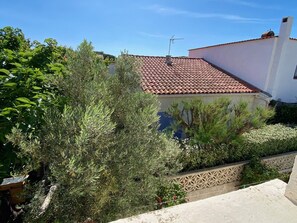 Ein Gebäude mit rotem Ziegeldach, umgeben von Grün und einer Zierwand.