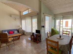 A living room with a sofa, chairs, a dining table, and a TV. - Air-conditioned apartment near sea - 6 guests (Port Leucate)