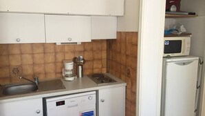 Eine kompakte Küche mit Kaffeemaschine, Mikrowelle und Kühlschrank.