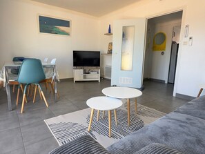 A modern living room with a TV, dining area, and a door leading to another room. - Air-conditioned apartment, port view - 6 guests (Port-Vendres)