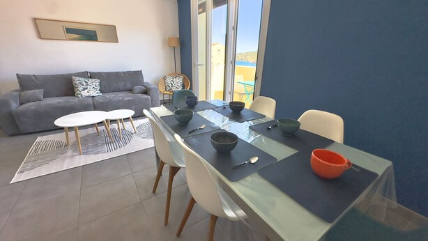 Een eethoek met een tafel, stoelen en een bank in een kamer met een groot raam en uitzicht.