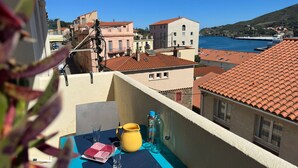 Een balkon met een tafel, een gele kruik en glazen.