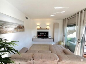 A modern living room with a large sectional sofa, a mounted flat-screen TV, and a painting on the wall. - Apartment with AC and Wi-Fi - 6 guests (Salou)