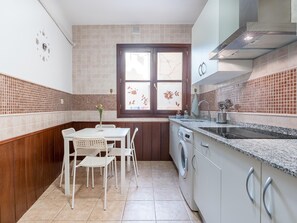 Eine kompakte Küche mit Essbereich, einer Waschmaschine und einem Fenster mit Verzierglas.