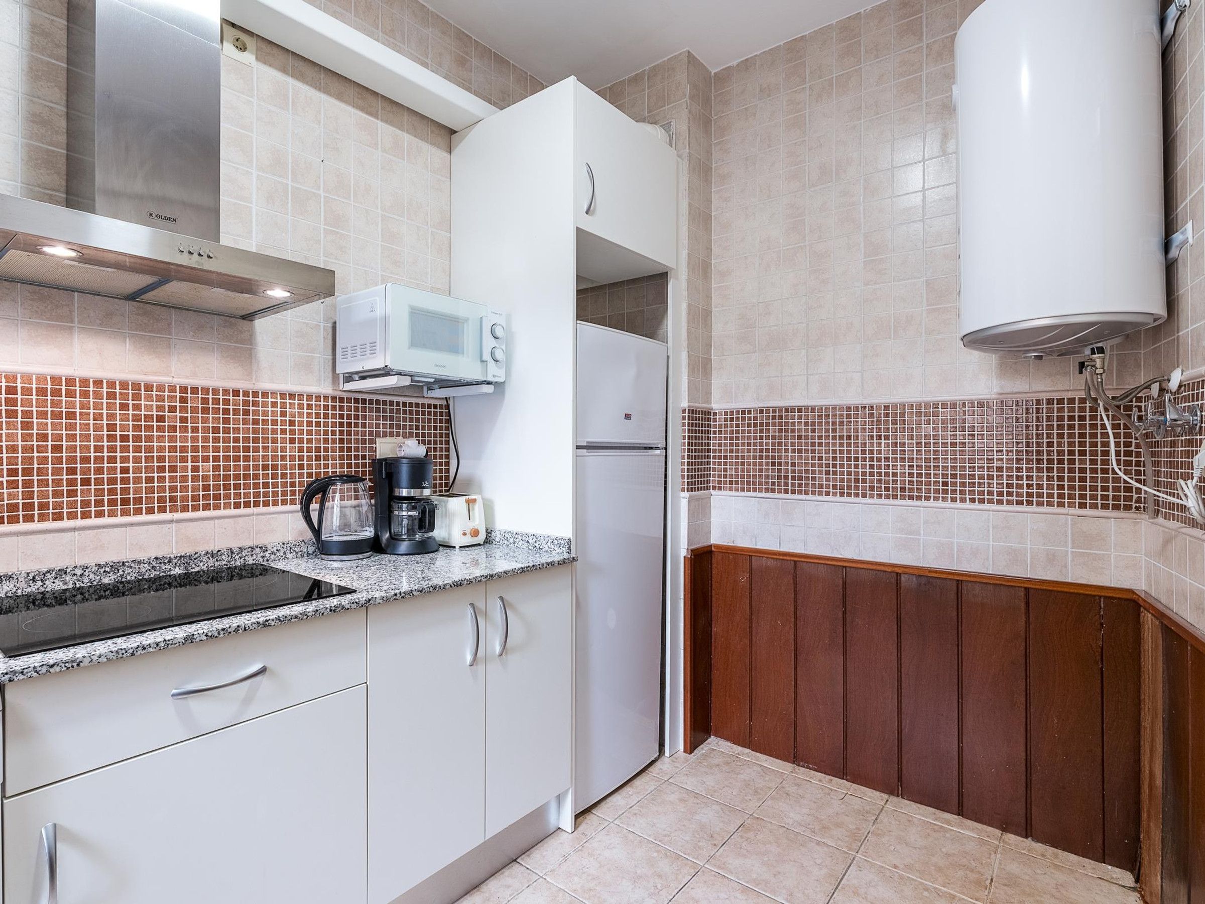 A kitchen with white cabinets, a microwave, a coffee maker, and a refrigerator.