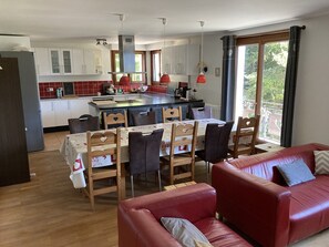 Une cuisine moderne avec un îlot central, un coin repas avec des chaises et un canapé en cuir rouge.