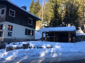 Een gebouw met twee verdiepingen, een ski-lodge, sneeuw bedekte grond en omliggende bomen.