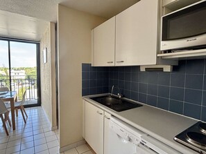 A compact kitchen with white cabinets, a Bosch dishwasher, a Brandt microwave, and a view of the outside. - Apartment near sea, elevator - 4 guests (Argelès-sur-Mer)