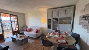 Ein Wohnzimmer mit einer Couch, einem Esstisch für vier Personen und einem Bücherregal.
