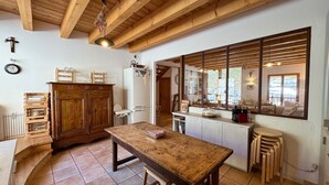 Una cocina rústica con vigas de madera, un ventanal grande y un comedor con mesa y sillas de madera.