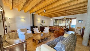 Una sala de estar acogedora con vigas de madera, chimenea y comedor con sillas y mesa.
