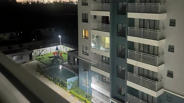 Um edifício com vários andares, varandas, piscina e parquinho.
