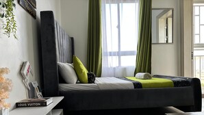 Quarto moderno com cama, cortinas verdes, um espelho e um livro Louis Vuitton.