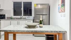 Een moderne keuken met een granieten aanrechtblad, roestvrijstalen apparatuur en een bar met krukken.