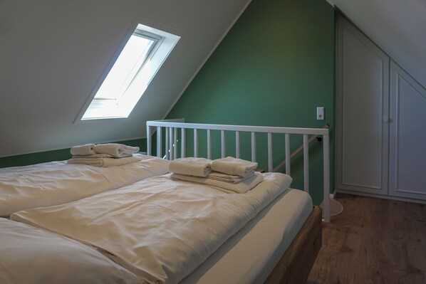 A room with two beds, a skylight, and a green wall. - Meeresleuchten on Sylt: relaxation, close to the beach, and space for 4 guests (Wenningstedt-Braderup (Sylt))