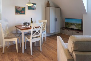 Een eethoek met een tafel, stoelen, een televisie en een kast.