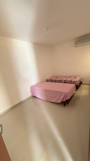 Ein Zimmer mit einem Bett, einem kleinen Tisch und einer Wand-Klimaanlage.