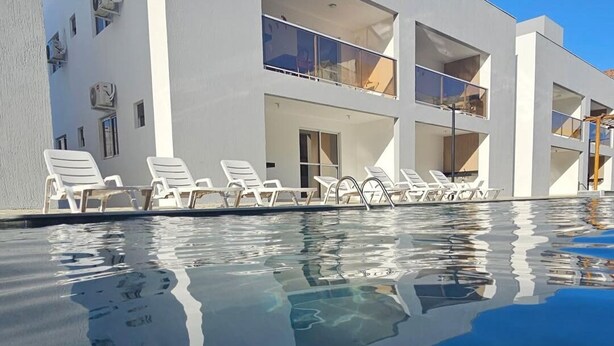 A modern building with a swimming pool, white walls, and multiple balconies. - Apartment in Jacumã (Balneário Novo Mundo, Praia de Jacuma, Conde)