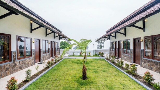 A courtyard with a central tree, surrounded by buildings with large windows and stone walls. - Bawangan Express  (Ngadisari)