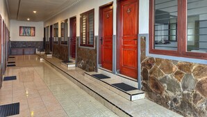 A hotel corridor with multiple doors, a stone wall, and a tiled floor. - Bawangan Express  (Ngadisari)