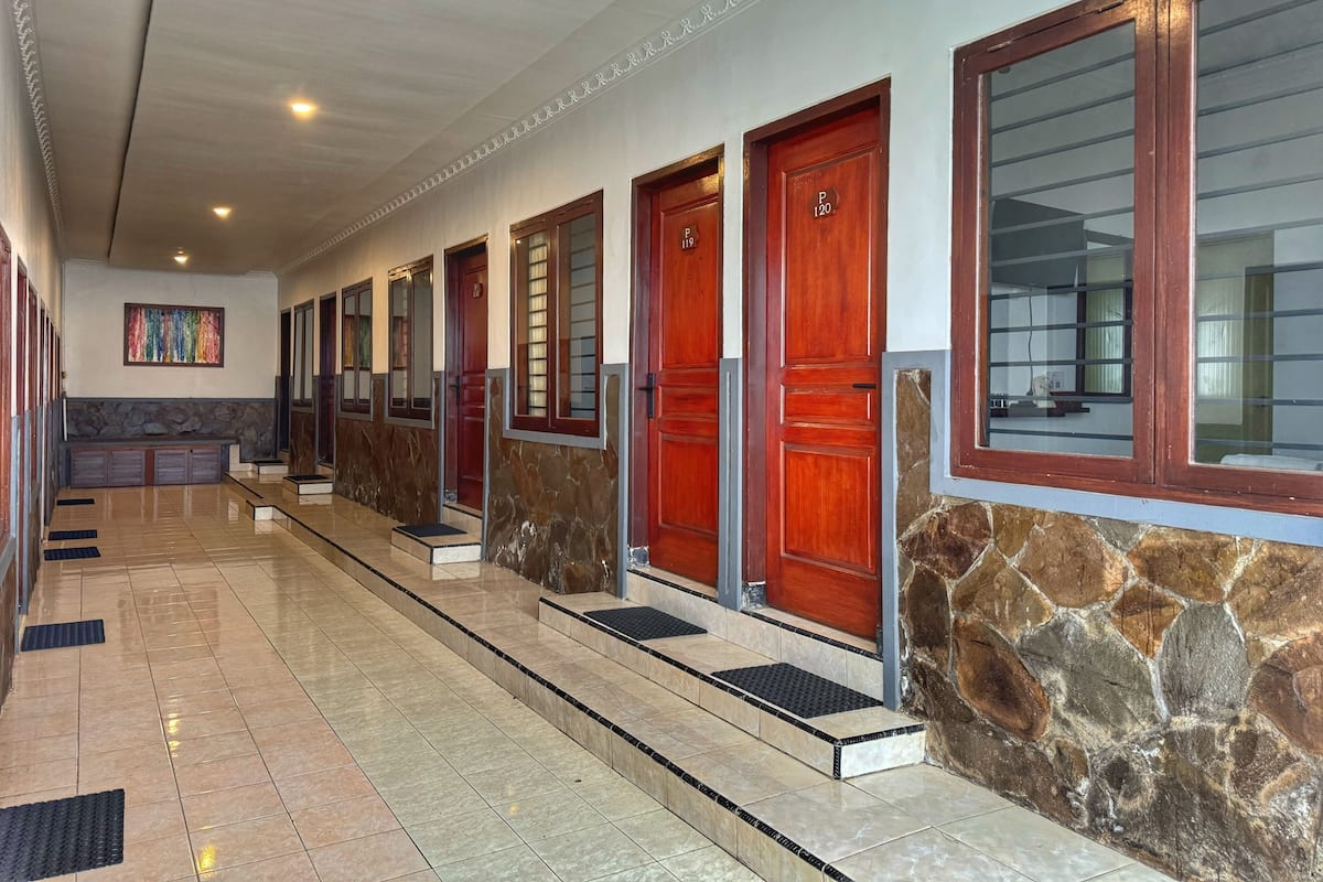 Un couloir d’hôtel avec de nombreuses portes, un mur en pierre et un sol carrelé.
