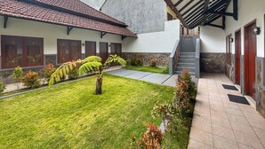 A building with a tiled roof, a covered walkway, and a small garden area with ferns and shrubs. - Bawangan Express  (Ngadisari)