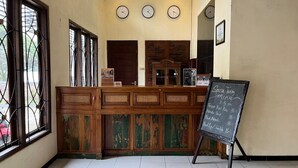 A reception desk with a chalkboard menu, clocks on the wall, and a wooden counter. - Bawangan Express  (Ngadisari)