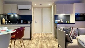A modern kitchen with a dining area, a sofa, and a TV. - KranichNest Schwimmhaus Uferhaus am Bodden – mit Terrasse & Seeblick für 4 Pers. (Ribnitz-Damgarten)