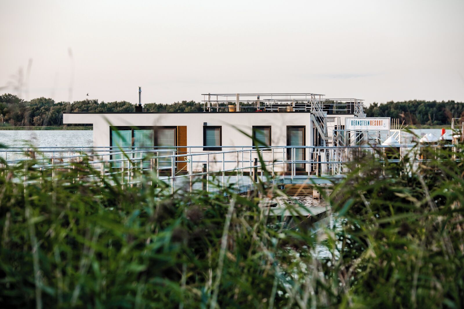 Een gebouw met een bord waarop 'Bernstein Resort' staat, en een waterpartij op de voorgrond.