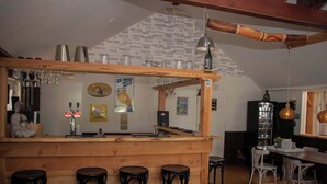 Eine Bar mit Hockern, einer Theke und einer Holzbalkendecke.