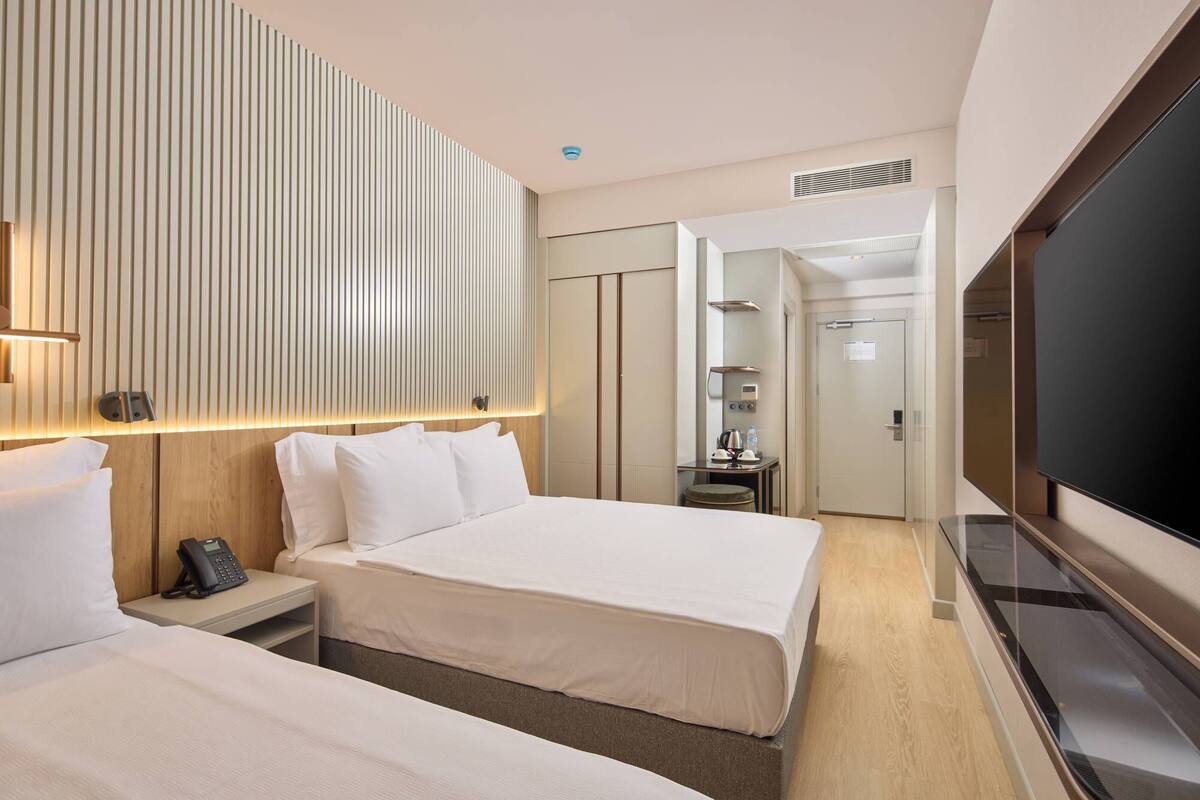 A hotel room with two beds, a TV, a phone, and a minibar.