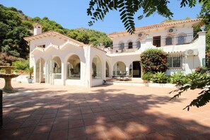 Ein zweistöckiges Gebäude mit Innenhof, Bogenarkaden und einem Garten.