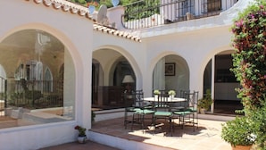 A courtyard with a dining area, arched windows, and a balcony. - Seven bedroom villa in Ojen near Marbella (Ojen)