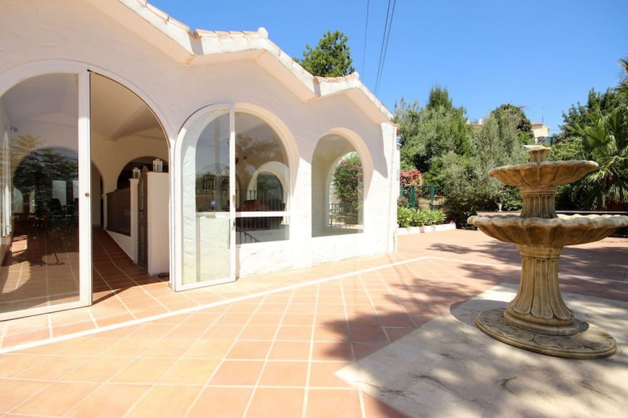 A building with a white exterior, large glass doors, and a tiled patio area.