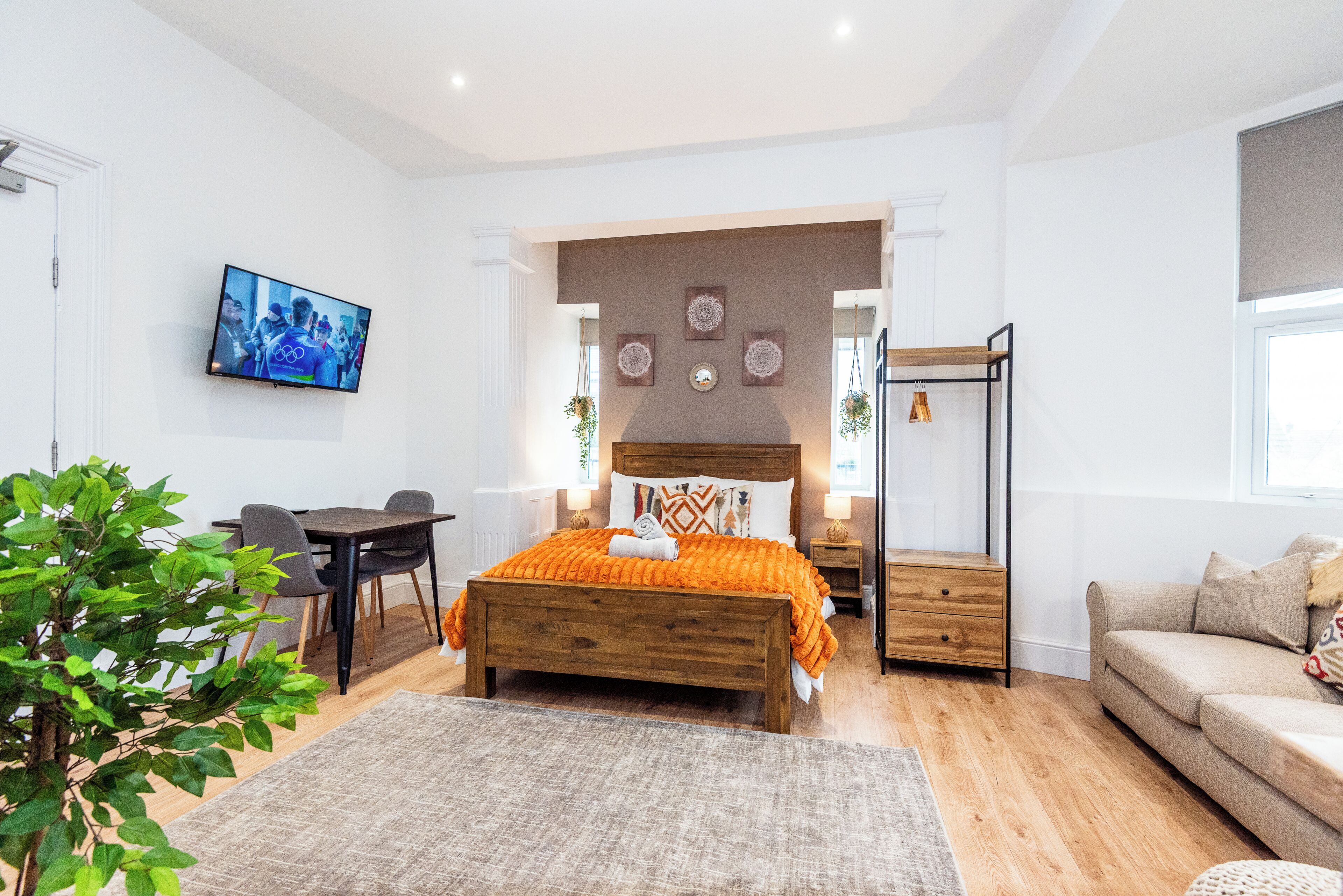Un dormitorio con cama, mesitas de noche, televisor, escritorio y sofá.