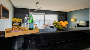 Eine moderne Küche mit schwarzem Arbeitsplatz, einer Wasserflasche, einer Tüte Snacks und einer Fruchtschale.