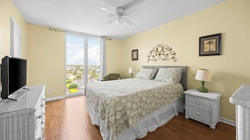 Une chambre à coucher avec un lit, une télévision, des meubles en osier et un balcon avec vue.