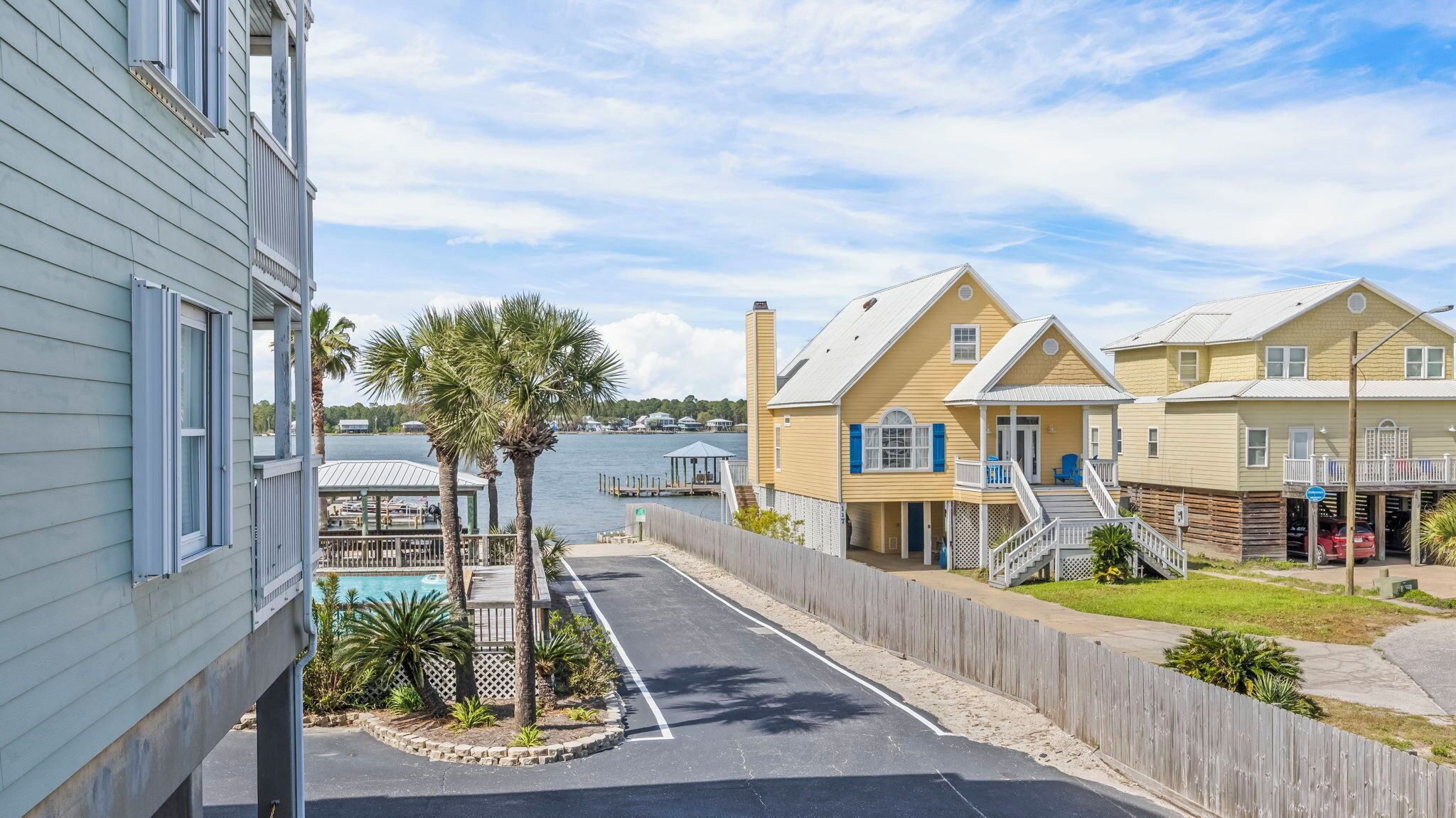 A waterfront property with a pool, wooden fences, and a view of the water.