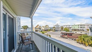 A balcony with chairs, a view of a beach, and a row of houses. - 2BR Condo w/ pool, lagoon view & deeded beach access - Sleeps 6 (Gulf Shores)