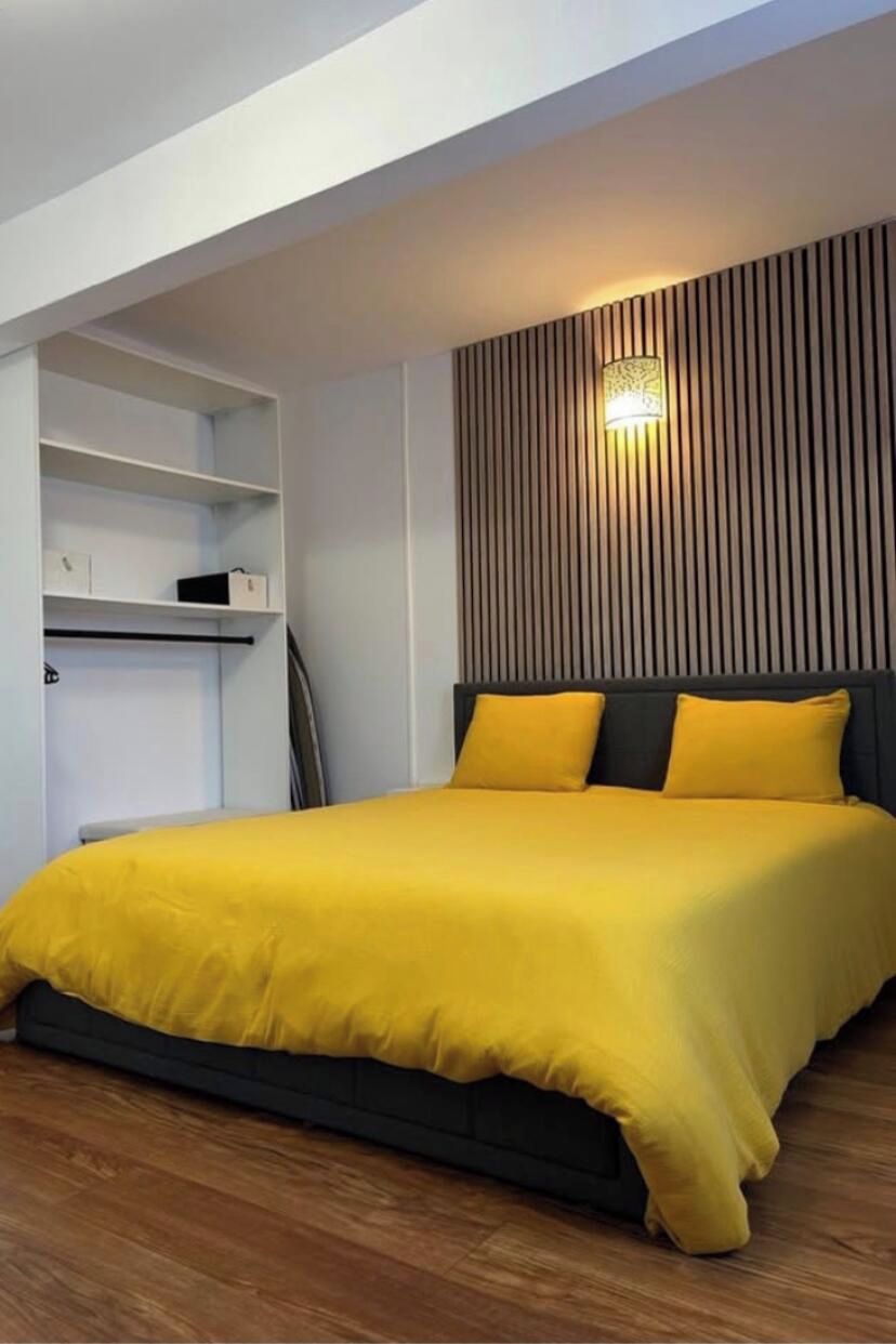 Een slaapkamer met een bed, een nachtkastje en een wandlamp.
