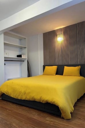 A bedroom with a bed, a bedside table, and a wall-mounted light fixture.