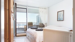 Ein Schlafzimmer mit Bett, Fenster, einem Gemälde und Blick nach draußen.