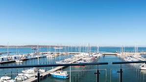 Ein Yachthafen mit mehreren Booten an Stegen, wolkenlosem Himmel und ruhiger See.