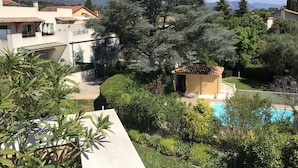 A residential area with a swimming pool, a large tree, and houses with red-tiled roofs.