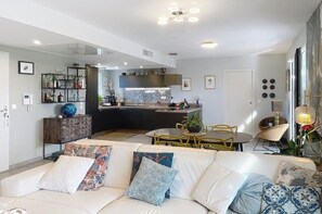 Un salon moderne avec un canapé, un coin repas et une cuisine en arrière-plan.