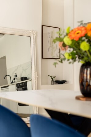 A modern kitchen with a white marble backsplash, a large white-framed mirror, and a black sink. - Marais Gem 2BR 6P Paris Stay (Paris)