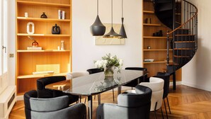 Un comedor con una mesa negra, sillas, un florero y una escalera espiral negra.